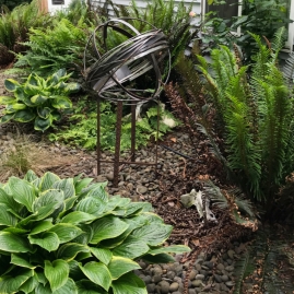 This Stainless Whirling Orb is set in a side yard rock garden.